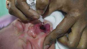 A health worker administers polio vaccine drops to a child at a hospital