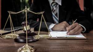 Tribunal attorney lawyer working with documents and wooden judge gavel on table in courtroom.