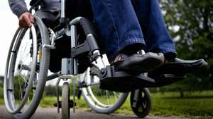 Man in wheelchair on path in park, low section