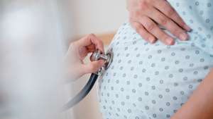 Doctor listening to belly of pregnant woman