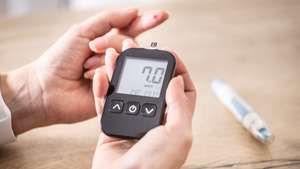 Close-up of woman hands measuring glucose level blood test with glucometer.