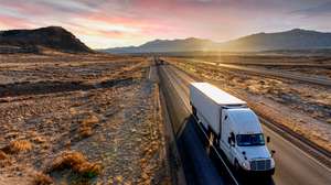 White Semi-Trailer Truck Heading down a four-lane Highway at Dusk