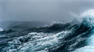 Breaking wave on a rough sea against overcast sky