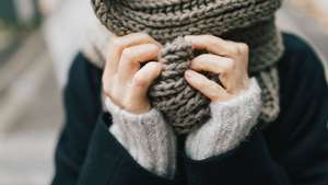 Woman&#039;s hand holding knitted scarf, close-up