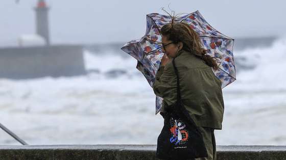 Uma mulher tenta proteger-se da chuva e do vento na marginal da Foz do Douro no Porto, 17 de outubro de 2023. Mais de 40 ocorrências foram registadas desde as 00:00 de hoje, a maioria na Grande Lisboa e em Setúbal, devido ao mau tempo, segundo informação disponível no ‘site’ da Autoridade Nacional de Emergência e Proteção Civil (ANEPC). ESTELA SILVA/LUSA