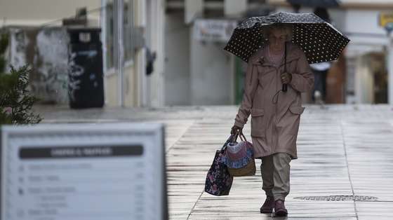 Mulher com chapéu de chuva na Costa de Caparica, Almada, 4 de novembro de 2024. CARLOS M. ALMEIDA/LUSA