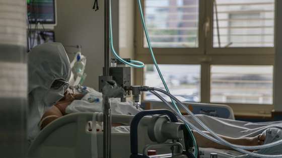 Uma enfermeira cuida de um paciente hospitalizado na Unidade de Cuidados Intensivos Covid 19 do Hospital Santa Maria em Lisboa, 27 de outubro de 2020. A urgência dedicada aos casos suspeitos de covid-19 do Hospital Santa Maria, em Lisboa, reflete a evolução da pandemia em Portugal com doentes a avolumarem-se à porta para realizar o teste e no interior a capacidade quase esgotada. O medo de perder o emprego leva muitos doentes com covid-19 a esconderem que estão infetados e a continuar a trabalhar, disseminando a doença que, nesta fase, começa a ser um caso também social e que leva a muitos internamentos no Santa Maria. (ACOMPANHA TEXTO DA LUSA DE 30 DE OUTUBRO DE 2020) TIAGO PETINGA/LUSA