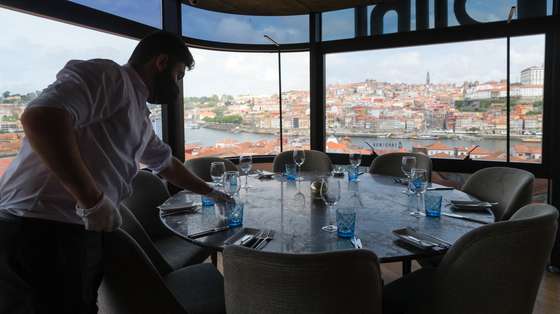 Um funcionário prepara uma mesa no restaurante The Blini no dia em que entram em vigor novas medidas de desconfinamento, Vila Nova de Gaia, 19 de abril de 2021. Passa a ser autorizada a abertura de restaurantes, cafés e pastelarias, mas com a restrição de lotação máxima a quatro pessoas ou seis pessoas em esplanadas e com horário até às 22:00 horas ou às 13:00 ao fim de semana. JOSÉ COELHO/LUSA