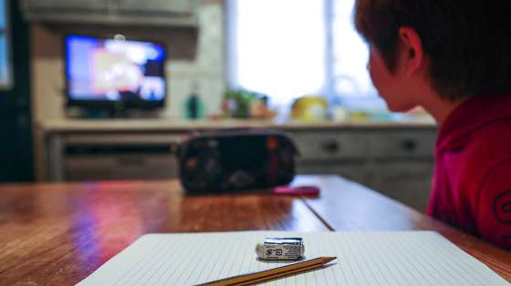 Uma criança do 1.º ano assiste na televisão à primeira aula de português ministrada através de uma emissão do programa #EstudoemCasa