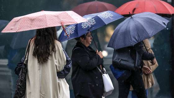 Jovens abrigam-se da chuva com um guarda-chuva junto ao Hospital São João, no Porto, 24 de setembro de 2024. De acordo com o Instituto Português do Mar e da Atmosfera (IPMA), prevê-se a ocorrência de períodos de chuva persistente a partir de hoje nas regiões Norte e Centro e que será por vezes forte na quarta e quinta-feira. ESTELA SILVA/LUSA