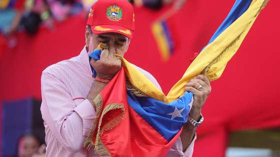 epaselect epa12563451 Venezuelan President Nicolas Maduro kisses a flag during a rally in Caracas, Venezuela, 01 December 2025. Maduro said that his country's power is based on the people, their guns, and their determination to build their homeland, at a time when tensions with the US have escalated due to the military deployment in the Caribbean and warnings about Venezuelan airspace, which have led to a wave of flight cancellations.  EPA/Miguel Gutierrez