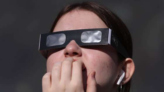 epa11996675 A woman uses protective glasses to watch a partial solar eclipse, at Greenwich Observatory in London, Britain, 29 March 2025. A solar eclipse happens when the Moon passes between the Sun and Earth, casting a shadow on Earth that either fully or partially blocks the Sun’s light in some areas.  EPA/NEIL HALL