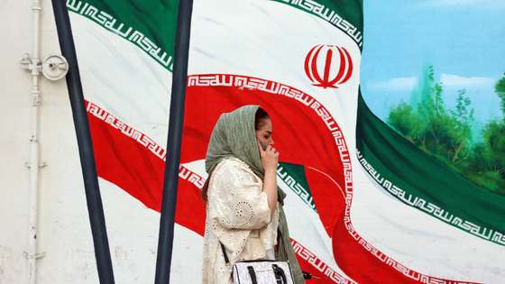 epa12121608 An Iranian woman walks past a wall painting of Iran's national flag in Tehran, Iran, 21 May 2025. Iran and US talks have paused as both sides made remarks against each other in recent days. According to the Iranian Foreign Ministry, Iranian Foreign Minister Abbas Araghchi said on 21 May 2025 that they are evaluating whether to participate in the next round of negotiations. He added that Iran has already responded to unreasonable demands and that such remarks do not help the talks. Our position is clear: uranium enrichment will continue, whether or not there is an agreement.  EPA/ABEDIN TAHERKENAREH