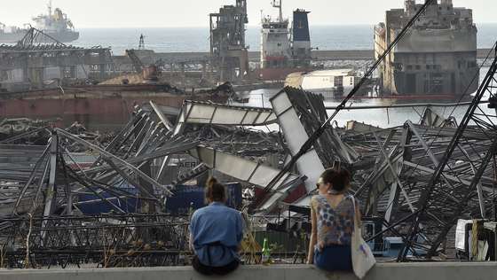 epa08599677 People look at the devastated harbor area after the explosion that hit Beirut port, in Beirut, Lebanon, 12 August 2020. Lebanese Health Ministry said at least 171 people were killed, and more than six thousand injured in the Beirut blast that devastated the port area on 04 August and believed to have been caused by an estimated 2,750 tons of ammonium nitrate stored in a warehouse.  EPA/WAEL HAMZEH