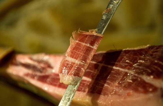 MADRID, SPAIN - DECEMBER 14:  An employee of the Alberto Lopez Araque jamon shop in Madrid cuts a slice of dry-cured Jamon Iberico de bellota (from acorn) on December 14, 2012 in Madrid, Spain. Dry-cured Iberian ham or Jamon Iberico is a favourite amongst Spaniards and producers are hoping for improved sales over the busy christmas period. The jamon Iberico de Bellota are usually dry-cured for up to three years after the pigs have been few on a diet of acorns in the last three months.  (Photo by Denis Doyle/Getty Images)