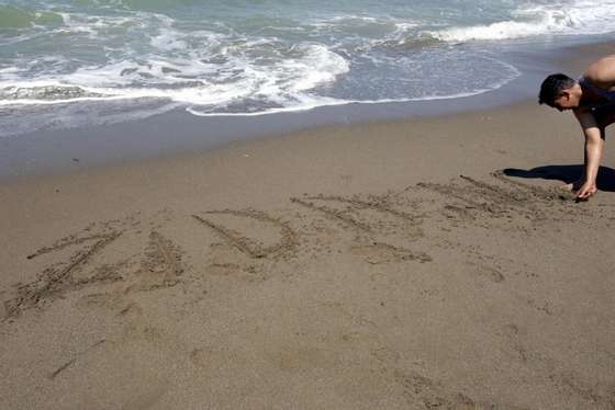 TICHY, ALGERIA:  An Algerian man scrawls French footballer Zinedine Zidane's name in the sand at the beach of Tichy town, 300 kilometersm east of Algiers 09 July 2006. Arguably the best footballer of his generation, the 32-year-old midfielder of Kabyle Algerian descent who has starred for both the French national team and for four club teams, officially announced his retirement after the 2006 FIFA World Cup.  (Photo credit should read FAYEZ NURELDINE/AFP/Getty Images)