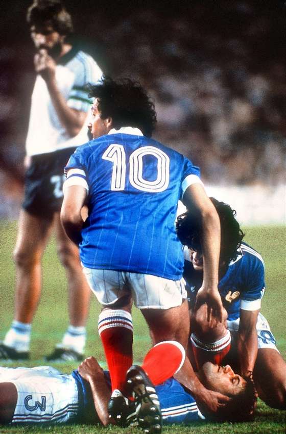 French defender Patrick Battiston lies on the ground as midfielder Michel Platini (10) and forward Didier Six surround him while waiting for the medical staff to come in 08 July 1982 in Sevilla during the World Cup semifinal soccer match between West Germany and France. West German goalkeeper Harald Schumacher charged into Battiston as he was going for the ball but was not thrown out by Dutch referee Charles Corver. West Germany beat France 5-4 on penalty kicks (1-1 at the end of regulation time; 3-3 at the end of extra time).  AFP PHOTO (Photo credit should read STAFF/AFP/Getty Images)