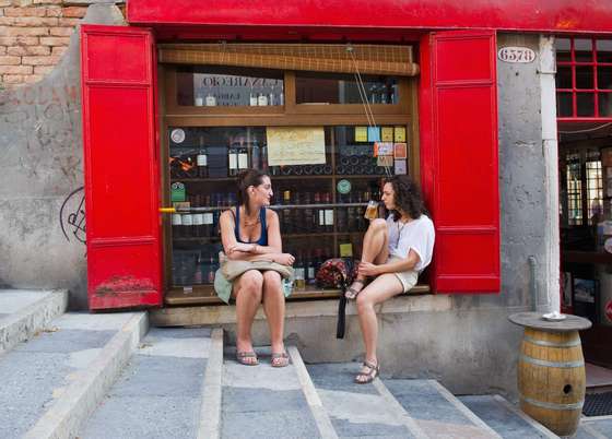 VENICE, ITALY - JUNE 17:  Two Venetians women enjoy a drink with "cicchetti" in front of a traditional bacaro on June 17, 2011 in Venice, Italy. The bacari, open just for lunch and dinner, are the local down to earth version of wine bars which serve 'ciccheti, a kind of Tapas traditionally washed down with a glass of wine, and Venetians stop to snack and socialize before and after meals. (Photo by Marco Secchi/Getty Images)