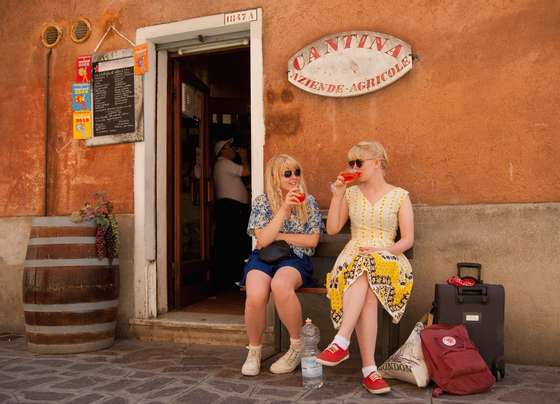 VENICE, ITALY - JUNE 17:  Two tourists enjoy a Spritz (a powerful mixture of white wine, Campari and soda water) in front of a traditiona bacaro on June 17, 2011 in Venice, Italy. The bacari are the local down to earth version of wine bars which serve 'ciccheti, a kind of Tapas traditionally washed down with a glass of wine, and Venetians stop to snack and socialize before and after meals. (Photo by Marco Secchi/Getty Images)