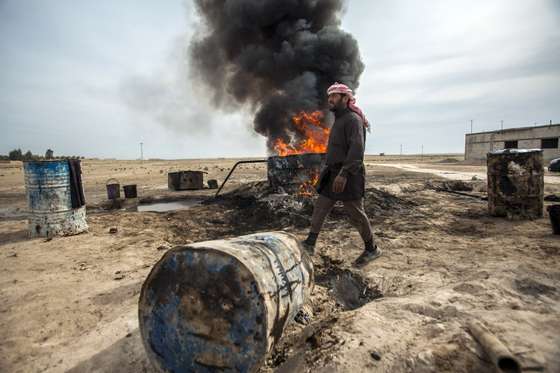 TO GO WITH AFP STORY BY JOSE MIGUEL CALATAYUD A picture taken on April 15, 2013 shows a Syrian man in the Al Raqqa countryside, who until three months ago was a farmer, pouring crude oil brought from Deir Ezzor province into a pit where it will be distilled as part of the refining process to produce fuel. Final products such as benzine and diesel are then sold to locals. Deir Ezzor contains the largest energy reserves in Syria, which produced some 420,000 of barrels of oil a day before the United States and the European Union banned the import of Syrian petroleum in 2011. AFP PHOTO/ALICE MARTINS (Photo credit should read ALICE Martins/AFP/Getty Images)