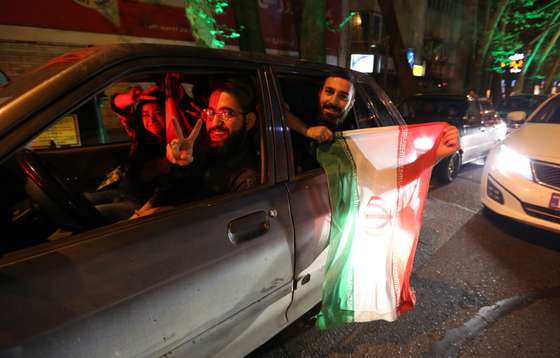 People flash the "V for Victory" sign and hold an Iranian flag out of a car window as they celebrate on Valiasr street in northern Tehran on April 2, 2015, after the announcement of an agreement on Iran nuclear talks. Iran and global powers sealed a deal on April 2 on plans to curb Tehran's chances for getting a nuclear bomb, laying the ground for a new relationship between the Islamic republic and the West. AFP PHOTO / ATTA KENARE        (Photo credit should read ATTA KENARE/AFP/Getty Images)