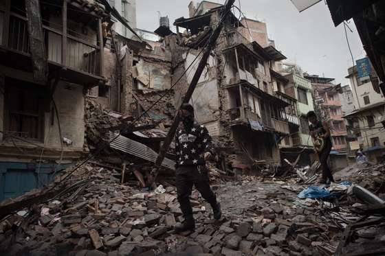 People walk among earthquake debris in the Nepalese capital Kathmandu on April 28, 2015.  Hungry and desperate villagers rushed towards relief helicopters in remote areas of Nepal on April 28, begging to be airlifted to safety, four days after a monster earthquake killed nearly 4,500 people.  AFP PHOTO / Nicolas ASFOURI        (Photo credit should read NICOLAS ASFOURI/AFP/Getty Images)