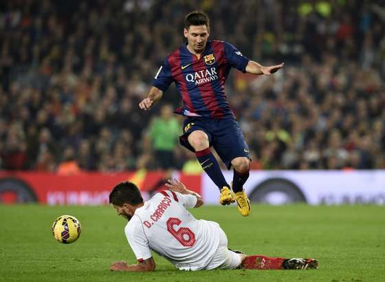 Barcelona's Argentinian forward Lionel Messi (top) jumps over Sevilla's Portuguese midfielder Daniel Carrico (L) during the Spanish league football match FC Barcelona vs Sevilla FC at the Camp Nou stadium in Barcelona on November 22, 2014.   AFP PHOTO / LLUIS GENE        (Photo credit should read LLUIS GENE/AFP/Getty Images)