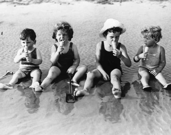 20th July 1935: A group of young children sit in the shallows as they enjoy an ice-cream at Littlehampton. (Photo by Reg Speller/Fox Photos/Getty Images)