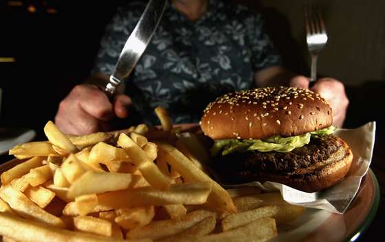 GLASGOW, UNITED KINGDOM - JUNE 07:  In this photo illustration a man eats a hamburger ind chips in a cafe on June 7,2006 in Glasgow, Scotland. New figures are suggesting that a large proportion of the population is clinically obese.  (Photo Illustration by Jeff J Mitchell/Getty Images)
