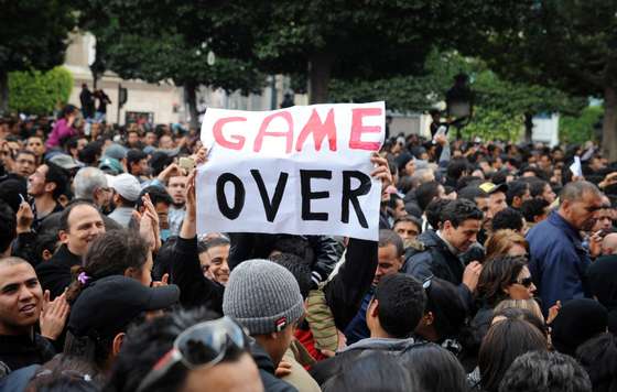 A tunisian demonstrator holds a placard reading "Game Over" during a rally in front of the country's Interior ministry in Tunis on January 14, 2011, to demand President Zine El Abidine Ben Ali's resignation. Ben Ali stepped down today after 23 years in power and fled the north African state as the authorities declared a state of emergency following deadly protests. Prime Minister Mohammed Ghannouchi announced on state television that he had taken over as interim president, after a day of violent clashes between rock-throwing protesters and riot police in the streets of central Tunis. AFP PHOTO / FETHI BELAID (Photo credit should read FETHI BELAID/AFP/Getty Images)