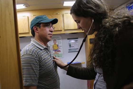 BRIGHTON, CO - APRIL 30: Physician's assistant Stephanie Miller checks the heart rate of an immigrant farm worker from Mexico during mobile clinic visit to a farm on April 30, 2013 in Brighton, Colorado. Salud family Health Centers sends a mobile clinic to farms throughout northeastern Colorado to serve the migrant population, many of whom ave little access to health care, which has become a major issue in health care reform proposals. (Photo by John Moore/Getty Images)