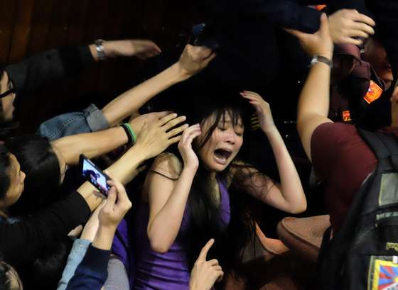 A protester shout as police officers try to remove the chairs displayed to block the entrance of the Taiwanese Parliament which is occupied by activists to protest against moves by the ruling Kuomintang party to ratify a contentious trade agreement with Chinain, in Taipei on March 19, 2014. Late on March 18 around 200 students and activists broke through a security barrier and took over the main chamber in Taiwan's parliament, singing and dancing in protest against the trade agreement. AFP PHOTO / SAM YEH (Photo credit should read SAM YEH/AFP/Getty Images)