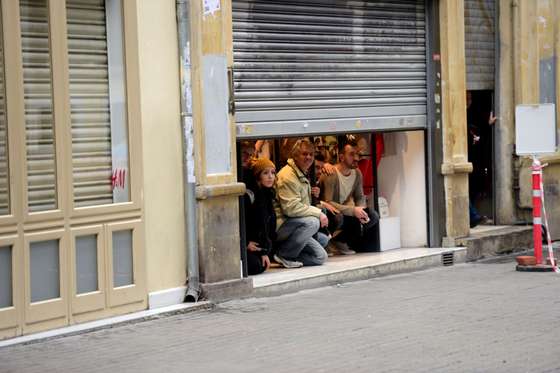People take shelter inside a shop after an explosion on the pedestrian Istiklal avenue in Istanbul on March 19, 2016. Two people, including the bomber, were killed and six others injured in a suicide attack on a major shopping street in Istanbul on Saturday, Turkey's CNN-Turk television reported. / AFP / Bulent KILIC (Photo credit should read BULENT KILIC/AFP/Getty Images)