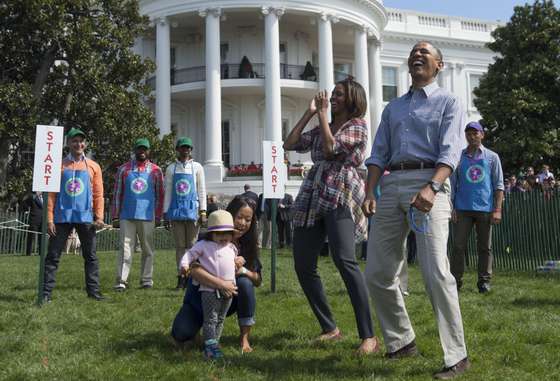 US President Barack Obama and First Lady Michelle Obama react to a child rolling an Easter egg during the annual White House Easter Egg Roll on the South Lawn of the White House in Washington, DC, April 21, 2014. The 126th annual White House Easter Egg Roll, the largest annual public event at the White House with more than 30,000 attendees expected, features live music, sports courts, cooking stations, storytelling and Easter egg rolling, with the theme, "Hop into Healthy, Swing into Shape." AFP PHOTO / Saul LOEB (Photo credit should read SAUL LOEB/AFP/Getty Images)