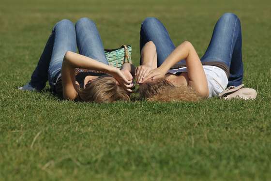 BERLIN, GERMANY - AUGUST 22: Two young women relax ona sunny day on grass near the Reichstag on August 22, 2011 in Berlin, Germany. Germany, which has thus far endured a summer marked by rain and cold, is seeing sunny skies and warm temperatures this week. (Photo by Sean Gallup/Getty Images)