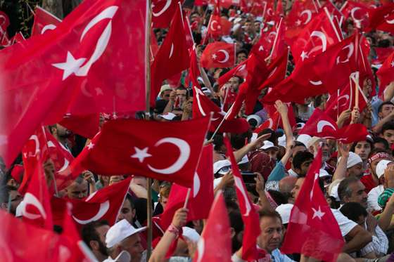 Supporters wave Turkish national flags as Turkish President (unseen) arrives during a rally near his house in Istanbul on July 16, 2016 after Turkish authorities wrested back control of the Ataturk airport.  President Recep Tayyip Erdogan urged Turks to remain on the streets on July 16, 2016, as his forces regained control after a spectacular coup bid by discontented soldiers that claimed more than 250 lives. Describing the attempted coup as a "black stain" on Turkey's democracy, Yildirim said that 161 people had been killed in the night of violence and 1,440 wounded. / AFP / GURCAN OZTURK        (Photo credit should read GURCAN OZTURK/AFP/Getty Images)