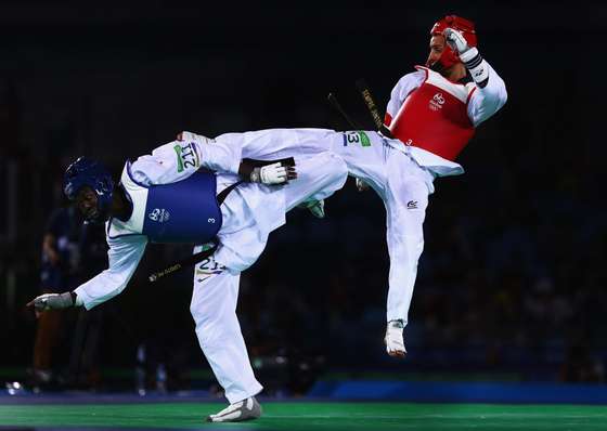 RIO DE JANEIRO, BRAZIL - AUGUST 17: Rui Braganca of Portugal kicks Luisito Pie of the Dominican Republic during the Taekwondo Men's -58kg Quarter Final contest at Cairoca Arena 3 on August 18, 2016 in Rio de Janeiro, Brazil. (Photo by Ryan Pierse/Getty Images)