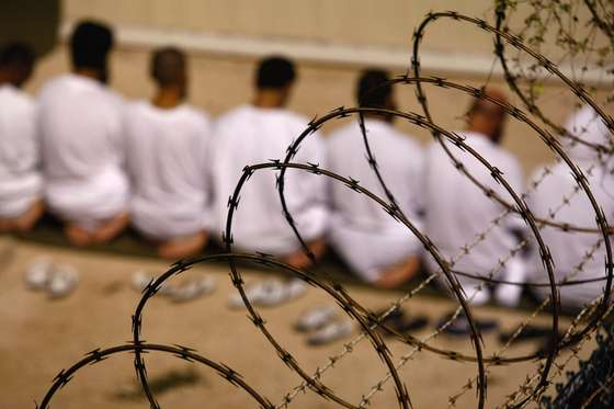 GUANTANAMO BAY, CUBA - OCTOBER 28: (EDITORS NOTE: Image has been reviewed by U.S. Military prior to transmission) A group of detainees kneels during an early morning Islamic prayer in their camp at the U.S. military prison for "enemy combatants" on October 28, 2009 in Guantanamo Bay, Cuba. Although U.S. President Barack Obama pledged in his first executive order last January to close the infamous prison within a year's time, the government has been struggling to try the accused terrorists and to transfer them out ahead of the deadline. Military officials at the prison point to improved living standards and state of the art medical treatment available to detainees, but the facility's international reputation remains tied to the "enhanced interrogation techniques" such as waterboarding employed under the Bush administration. (Photo by John Moore/Getty Images)