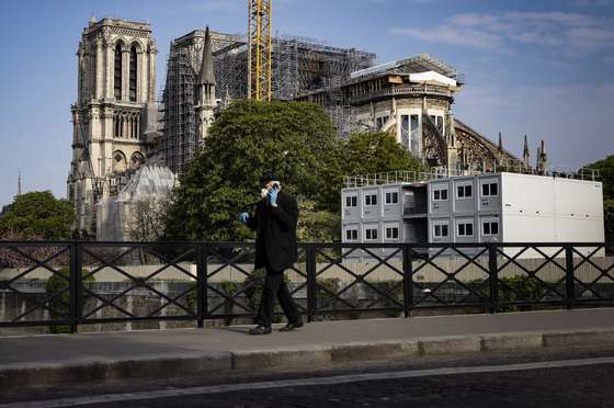 epa08358419 A man wearing protective gloves and a face mask walks past Notre-Dame Cathedral on Easter Sunday, in Paris, France, 12 April 2020. Easter and religious celebrations are held behind closed doors as France is under lockdown in an attempt to stop the widespread of the SARS-CoV-2 coronavirus causing the Covid-19 disease.  EPA/IAN LANGSDON