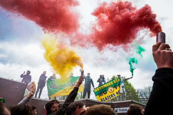 Football fans burn flares outside the Old Trafford during a