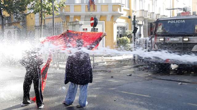 epa13309477 Protestors waving Albanian flags confront riot police officers during a student demonstration in Tirana, Albania, 16 October 2026. Tens of thousands of university students took to the streets to protest rising education costs, deteriorating campus conditions, and alleged government corruption under Prime Minister Edi Rama.  EPA/MALTON DIBRA