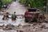 epa13290575 People walk through an area affected by a mudslide in Las Condes, Chile, 08 October 2026. Chile's National Disaster Prevention and Response Service (Senapred) said intense rainfall triggered the mudslide after ravines in the area were activated, sweeping away vehicles and a public transport bus.  EPA/JAVIER TORRES