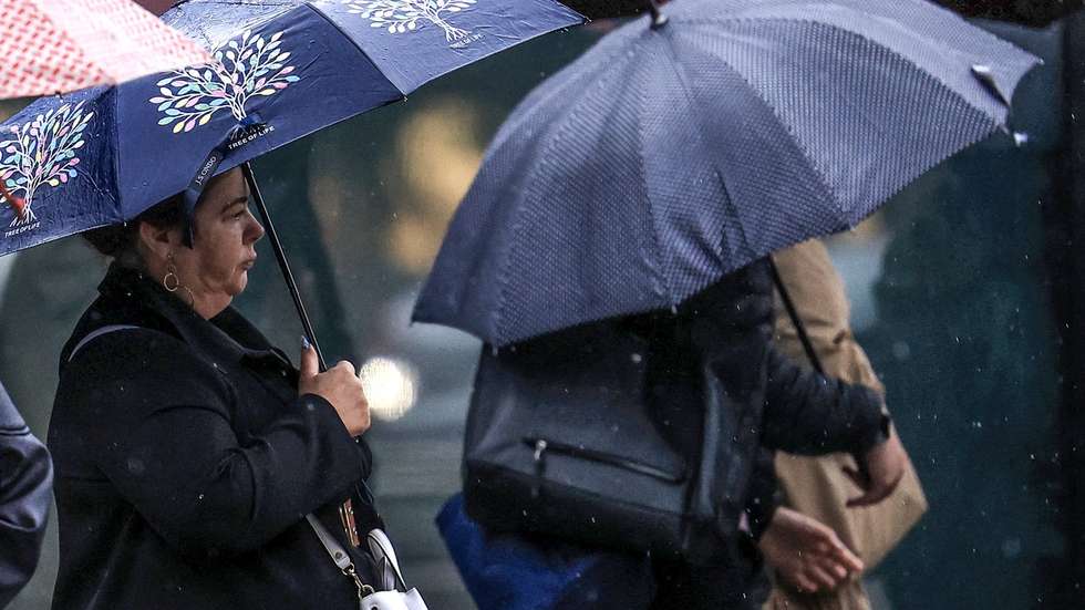 Jovens abrigam-se da chuva com um guarda-chuva junto ao Hospital São João, no Porto, 24 de setembro de 2024. De acordo com o Instituto Português do Mar e da Atmosfera (IPMA), prevê-se a ocorrência de períodos de chuva persistente a partir de hoje nas regiões Norte e Centro e que será por vezes forte na quarta e quinta-feira. ESTELA SILVA/LUSA