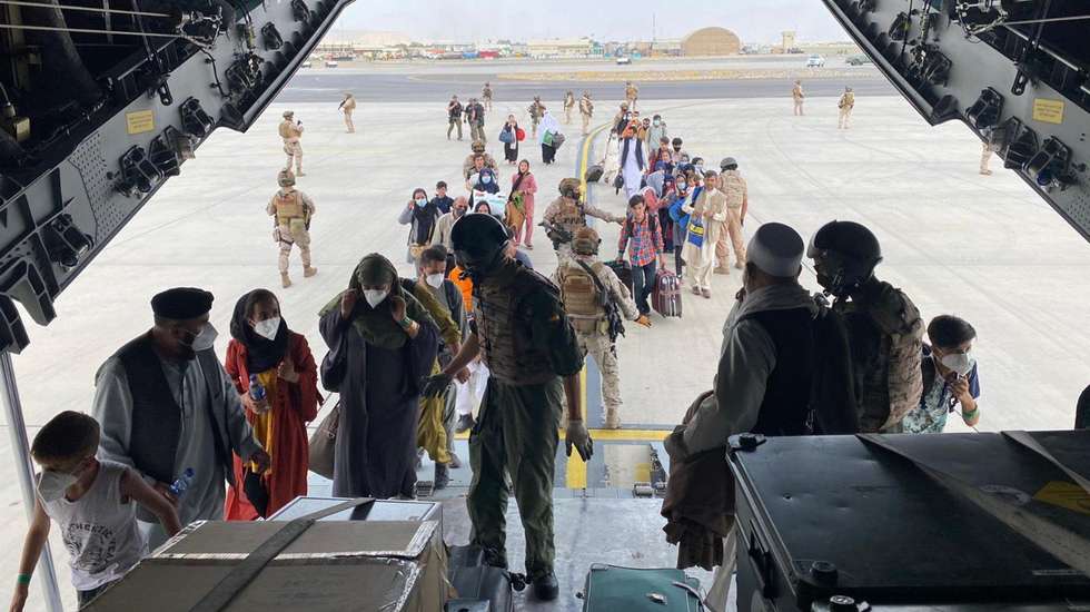 epa09419087 A handout photo made available by the Spanish Defense Ministry shows Spanish soldiers helping people board an Airbus A400M at the airport in Kabul, Afghanistan, 18 August 2021. This is the first aircraft of a total of three that will be helping in the evacuation of Spanish nationals as well as Afghans that have collaborated with Spain during the last years together with their families.  EPA/Spanish Ministry of Defense HANDOUT  HANDOUT EDITORIAL USE ONLY/NO SALES