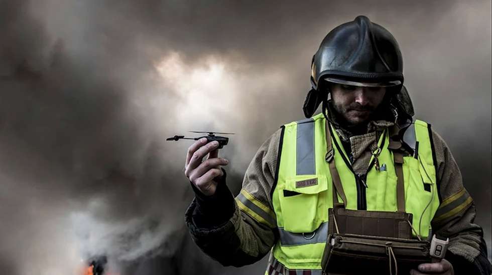 Bombeiros segura drone Black Hornet entre os dedos enquanto prepara operação