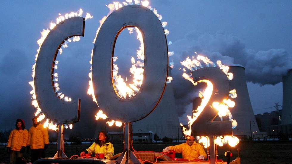 Membros da Greenpeace manifestam-se contra as estações de emissão de carbono ao queimarem as letras "CO2"