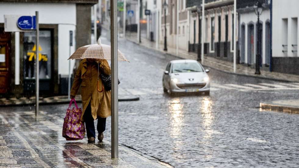 Uma popular protegida por um guarda-chuva passa pela rua do Galo, deserta de pessoas, devido aos efeitos que já estão a ser sentidos, com o aumento gradual do vento e chuva nos grupos central e oriental do arquipélago dos Açores, da passagem do furacão Alex, na Praia da vitória, Ilha Terceira, 15 de janeiro de 2016. Segundo o IPMA  Instituto Português do Mar e da Atmosfera, o período mais crítico ocorrerá entre as 08:00 e as 11:00 de hoje (hora local, menos uma hora do que em Lisboa), quando se prevê a sua passagem em cima do arquipélago. ANTÓNIO ARAÚJO/LUSA