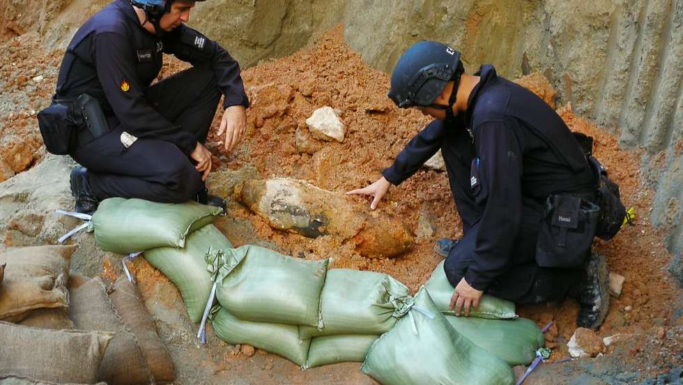 epa08549672 A photograph provided by the Hong Kong Police Force shows officers from the Explosive Ordnance Disposal Bureau inspecting a suspected World War 2 bomb found at a construction site in Kai Tak, Hong Kong, China, 16 July 2020. About 2,000 people have been evacuated after the suspected wartime bomb, about a metre long, was unearthed at the construction site.  EPA/HONG KONG POLICE FORCE HANDOUT  HANDOUT EDITORIAL USE ONLY/NO SALES