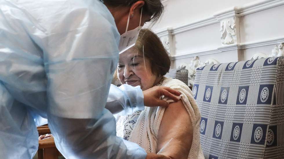 Uma utente de um lar de terceira idade é vacinada por uma enfermeira com a quinta dose da vacina contra a covid-19, em Lisboa, 19 de maio de 2022. TIAGO PETINGA/LUSA