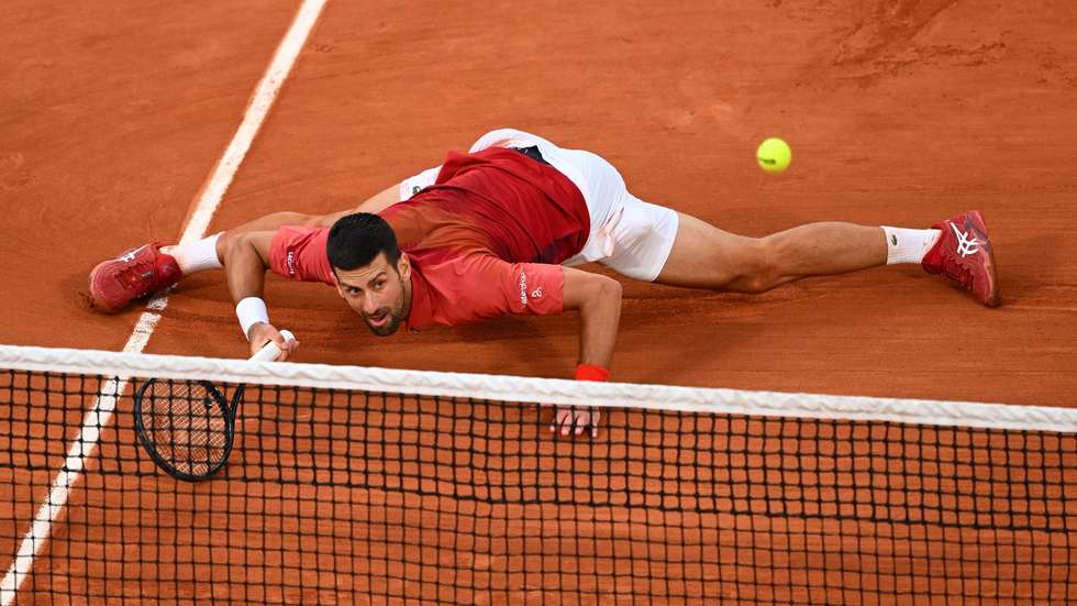 Novak Djokovic caiu algumas vezes no court queixando-se do excesso de pó de tijolo mas a última queda deu um ponto vital para a vitória em cinco sets